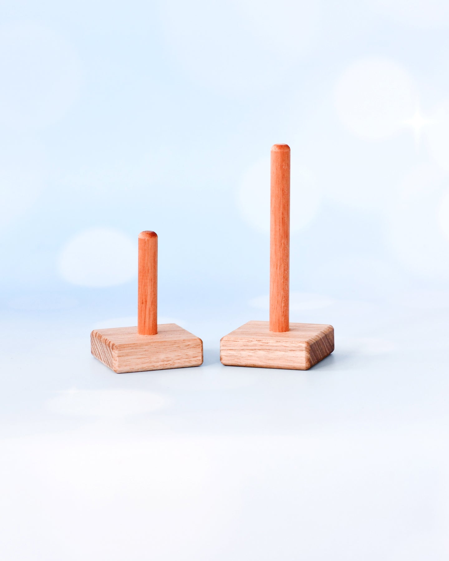 Two wooden stand-up toys with vertical sticks on a light blue background